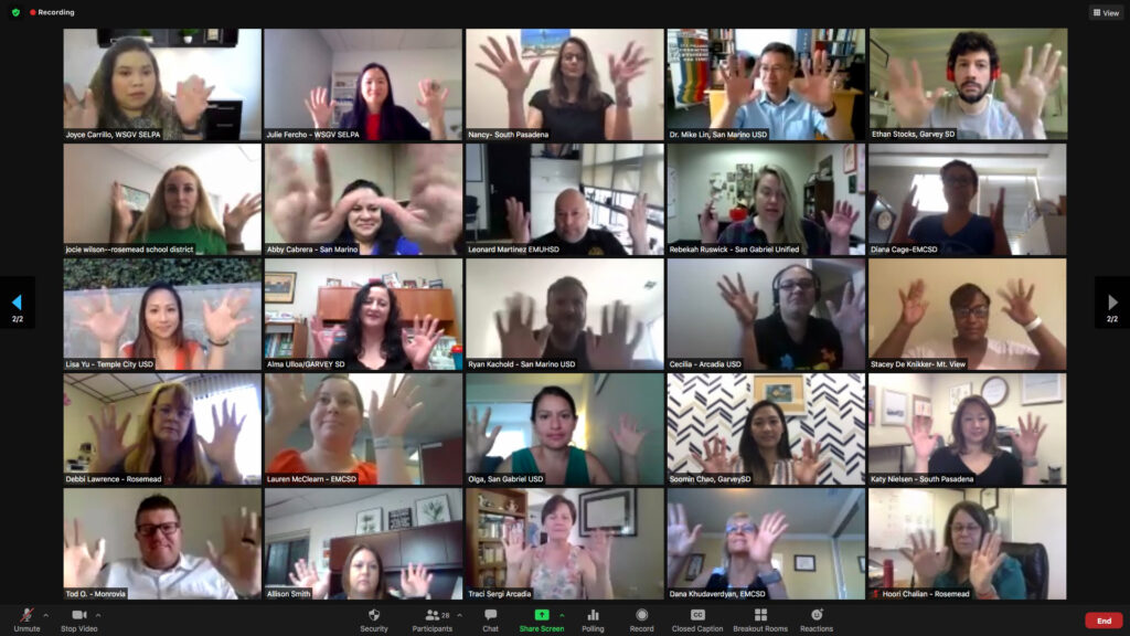 Screen shot of Zoom training participants smiling and all holding their hands up in what appears to be a "jazz hands" gesture.